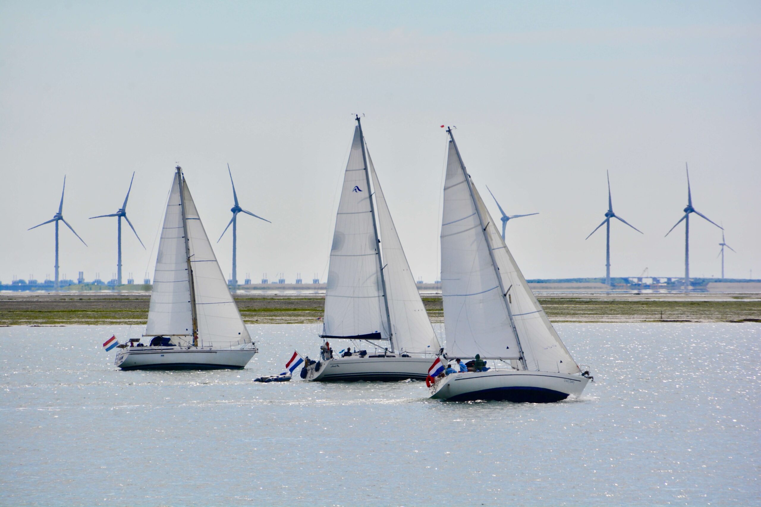 Afvalcontainer huren in Zeeland Zeilers op water met windmolens op de achtergrond